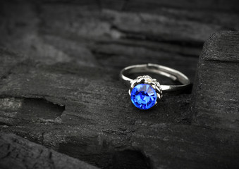 jewellery ring witht big blue sapphir on dark coal background, s