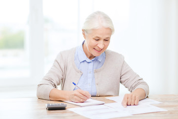 senior woman with papers and calculator at home