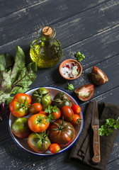 fresh tomatoes, garden herbs and olive oil on a dark wooden surface