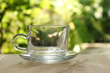 Empty clear glass of tea on bokeh green leaf background.