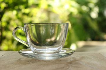 Empty clear glass of tea on bokeh green leaf background.