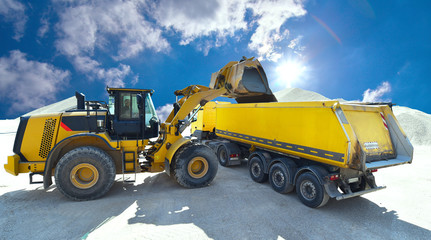 Obraz na płótnie Canvas Radlader belädt LKW mit Baumaterial in einem Kieswerk // excavator loads trucks with construction material in a gravel pit