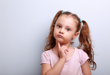 Fun confused kid girl thinking and looking serious about on blue