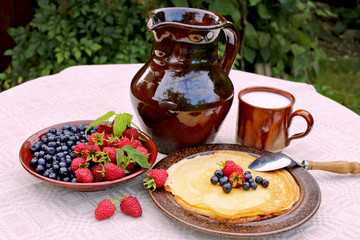 Pancakes  with raspberries, blueberries, milk, honeycomb and jug with milk