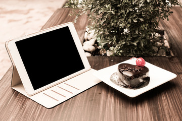 Chocolate cake and tablet in cafe
