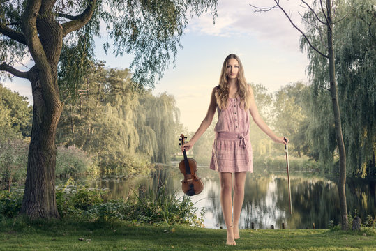 Junge Frau mit ihrer Geige steht an einem See