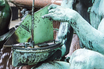 Statue hands hold a boat and place it on water