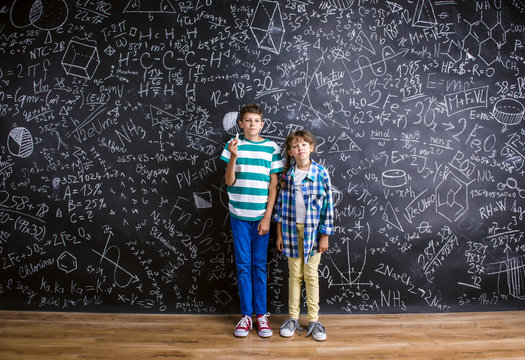 Cute little boy and girl in front of a big blackboard.