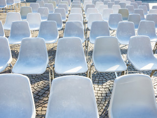 White plastic chairs waiting for audience at an open-air event