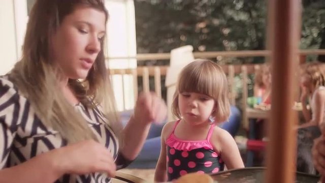 A mother gives her daughter a hug while they're eating a barbecue dinner
