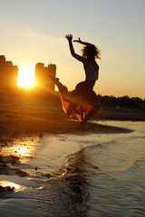 Silhouette of young girl, jumping  against of sea sunset .Freedom concept
