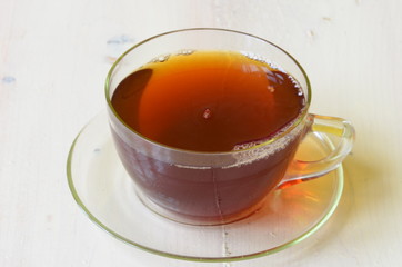 Cup with black tea on white wooden background