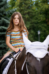 Fototapeta na wymiar Little girl riding festive horse
