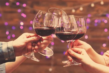 Crédence de cuisine en verre imprimé Vin Verres de vin rouge dans les mains sur fond de lumières vives