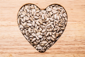 Heart shaped sunflower seeds on wood surface