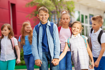 Group of kids with rucksacks near school building