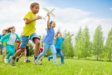 Fototapeta premium Happy girl holding airplane toy and children near