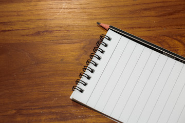 Note book and pencil on wooden office table