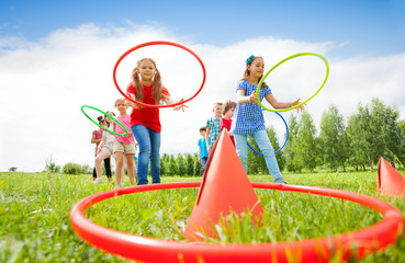 Kids throw colorful hoops on cones while competing