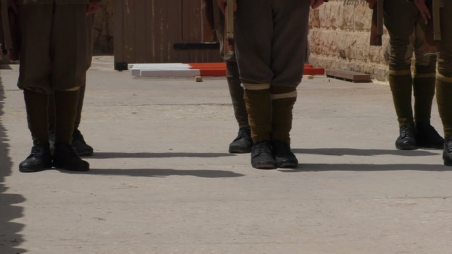 Unit of soldiers dressed in WW1 era khaki colour uniforms with rifles and bayonets are training outdoors