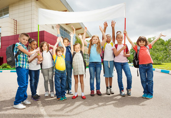 Obraz premium Group of happy children with arms up hold placard