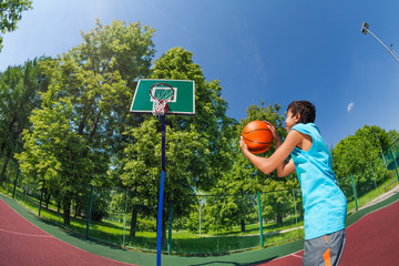 Arabian boy holds ball to throw in basketball goal
