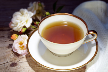 tea in a white porcelain cup with a gold rim and rose decoration