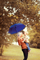 Family in autumn! Happy mother and child with umbrella having fu