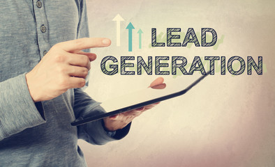 Young man pointing at Lead Generation text over tablet computer