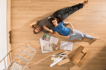 Top view, a modern couple lying on the floor of their new home