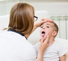 little boy having his throat examined by health professional