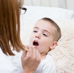 little boy having his throat examined by health professional