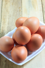 The eggs in foam box on the wood background.
