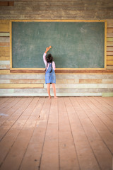 Fototapeta na wymiar Little girl clear the old green chalkboard