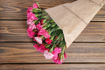 Beautiful bouquet of pink carnation on wooden table close up