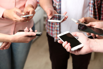 Many hands holding mobile phones close up