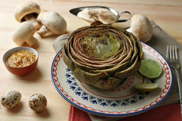 Boiled artichokes on plate, on color wooden background