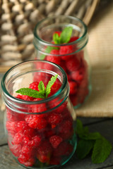 Sweet raspberries in glass jar on wooden  background