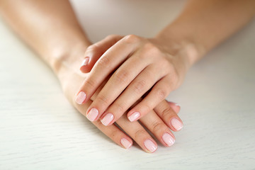 Woman hands with french manicure on table close-up