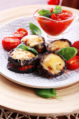 Fototapeta na wymiar Dish of eggplant with cherry tomatoes and cheese in white plate on wooden table, closeup