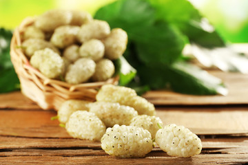 Fresh mulberry in wicker basket on wooden table, closeup