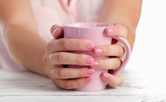 Woman's hand holding pink cup.