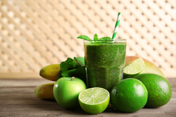 Green healthy juice with fruits and herbs on wooden background