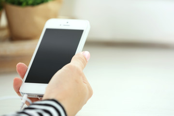 Music smartphone in female hand, on light background