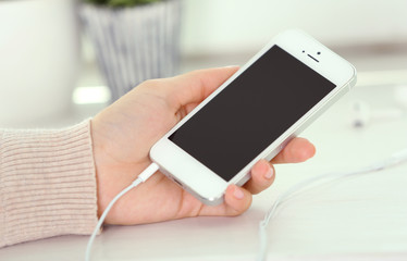 Music smartphone in female hand, on light background
