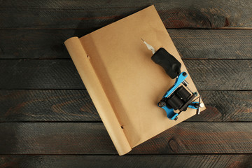 Machine for tattoo with old notebook on table close up