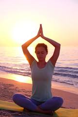 Fototapeta na wymiar Young healthy woman practicing yoga on the beach at sunset