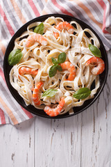 fettuccini pasta in cream sauce with shrimp on a plate. vertical top view
