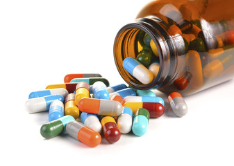 Pill bottle spilling pills on to surface isolated on a white bac