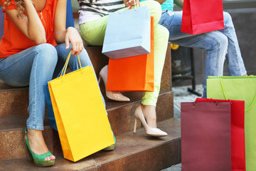 Beautiful young women with shopping bags sitting on steps